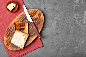 Wooden board with toasted bread on table