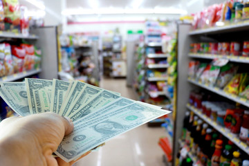 A hand holding dollars in shop. A man holding dollars for cash  in store. Money for sales exchange. Photo concept  finances and money.