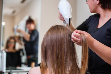 Hairdresser dries hair with a hairdryer in beauty salon