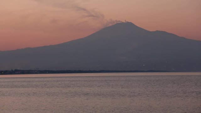 Beautiful sunset twilight on Agnone Bagni sea beach with smoky Etna volcano in far (Siracusa, Sicily, Italy)
