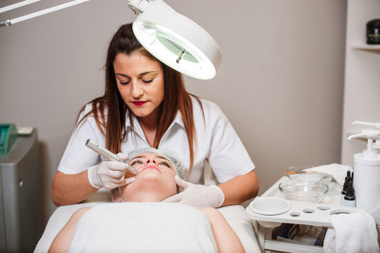 The doctor-cosmetologist makes a procedure of ultrasound cleaning of the facial skin