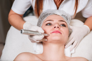 The doctor-cosmetologist makes a procedure of ultrasound cleaning of the facial skin