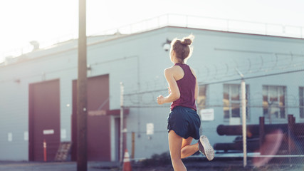 Woman jogging at sunset at industrial city area