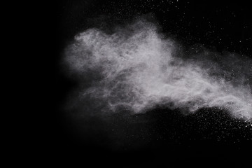Freeze motion of white dust explosion on black background. Stopping the movement of white powder on dark background. Explosive powder white on black background.