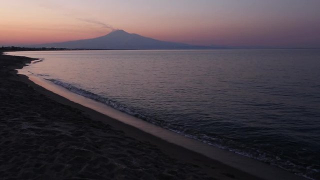 Beautiful sunset twilight on Agnone Bagni sea beach with smoky Etna volcano in far (Siracusa, Sicily, Italy)