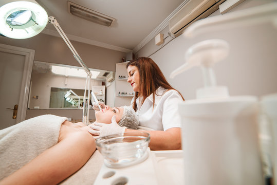 The doctor-cosmetologist makes a procedure of ultrasound cleaning of the facial skin