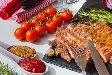 Fresh grilled meat. Cutting grilled beef entrecote medium roast on black stone board. Top view.