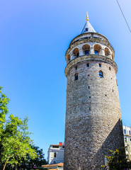 Obraz premium The tall and mighty Galata tower in Turkey, Istanbul. Shot against a beautiful blue sky with a slight hint of Cirrus clouds