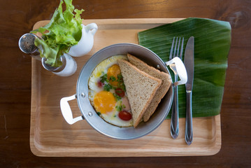 Breakfast,pan-fried egg, pan omelet with bread and Food Accessories on wooden tray for service in Thai restaurant.