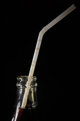 The neck of a cola bottle with a straw