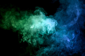 Thick colorful smoke of  blue and green on a black isolated background. Background from the smoke...