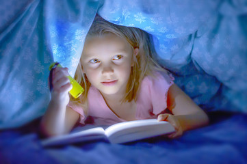 sweet beautiful and pretty little blond child girl 6 to 8 years old lying under bed covers reading...