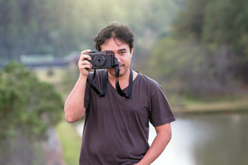 Portrait of young photographer over the forest with lake background,