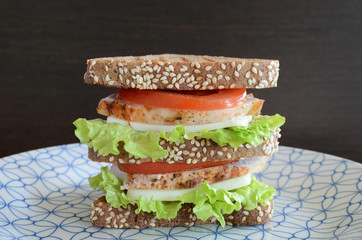 Sandwich of triangular bread with chicken breast tomato and cheese Black background