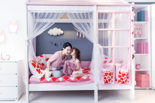 Cute little girl and her mother play in the bedroom