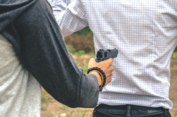 Portrait of Asian scared man Hostage of terrorist or burglar threatened by a gun point to man.Criminal and robbery for man safety concept.