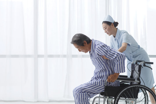Nurse helping senior man sitting in wheelchair