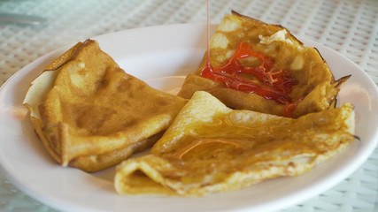 Pancakes on plate on which fruit syrup is poured. Pancakes on a plate with jam or topping.