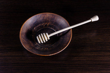 Honey spoon in the ceramic dish on dark wooden table
