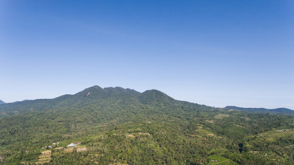 Aerial view of landscape, mountains covered with green forest, trees with sky and clouds, Bali,Indonesia. Slopes of the mountains are covered with forest in Asia. Travel concept.