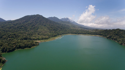 Obraz premium Aerial view of Lake Tamblingan, a caldera lake at Bali. Beautiful lake with turquoise water in the mountains of the island of Bali. Landscape, lake among mountains, sky, clouds.