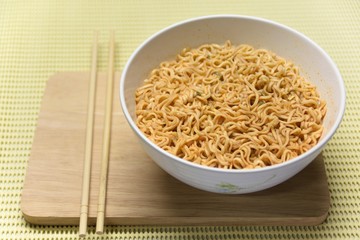 Instant noodles spicy in the cup with the chopsticks. Put on a plank of wood, ready to eat.