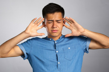 Annoyed young man plugging ears with hands