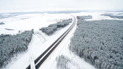 Fototapeta na wymiar Winter forest and the road. View from above. The photo was taken with a drone. Pine and fir forest in the snow