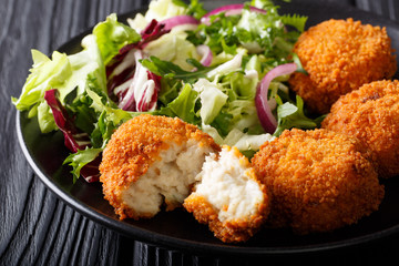 Delicious fish appetizer: cod cake in breading with fresh salad close-up. horizontal