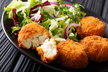 Freshly cooked cod cake in breading with fresh salad close-up on a plate. horizontal