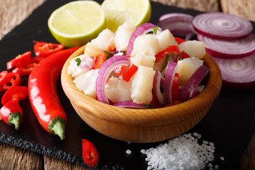 Freshly prepared ceviche from white fish with onions and peppers close-up in a bowl on the table. horizontal