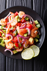 Spicy shrimp ceviche with vegetable salsa close-up on a plate. Vertical top view