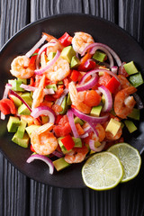 Seviche from marinated shrimp with avocado, pepper, tomatoes and onion close-up. Vertical top view