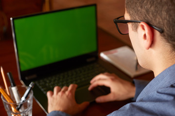 Back view of freelancer man in glasses working with laptop. Green screen. Caucasian businessman doing project on pc. Copyspace and product placement.