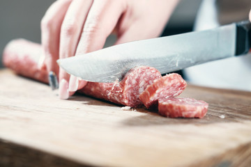 sausage, knife, hands of woman, slicing sausage, thick pieces, wooden plank,  knife in female...