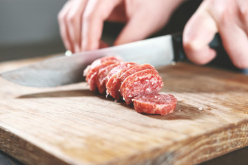 sausage, knife, hands of woman, slicing sausage, thick pieces, wooden plank,  knife in female...