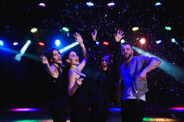 Four friends making having fun among confetti