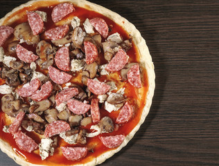 pizza cooking, meat of chiken, sausage salami, thick dough,  pizza crust, pizza is on a dark table, pizza with chicken and sausage salami, cooking process, mushrooms,  Champignon