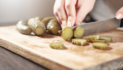 cook cuts pickled cucumbers, knife in female hands, cooking process, beautiful little cucumbers,...