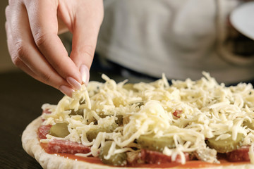 chef sprinkles cheese pizza,  a lot of cheese on a pizza,  cooking process, woman holding cheese in hands,  close-up,  homemade pizza,