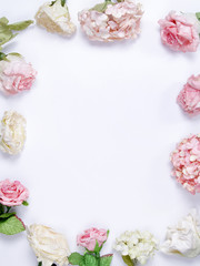 Fototapeta na wymiar Frame made of pink and beige roses, hydrangea, green leaves, branches on white background. Flat lay, top view. Wedding's background. Valentines day background with copy space.