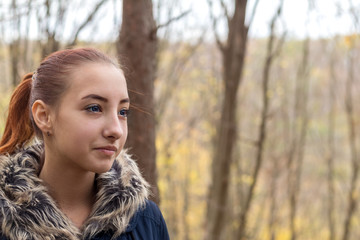 Fototapeta premium Cute beautiful pretty redhead female teenager in autumn forest. Close up charming portrait, shallow depth of field, toned.