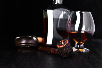 Glass of whiskey with smoking cigar.