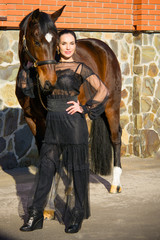 Beautiful stylishly dressed woman with a thoroughbred horse. The concept of love of horses and ladies lifestyle
