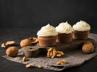 Carrot cupcakes or muffins with nuts on dark background