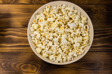 Bowl with popcorn on wooden table