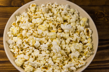 Bowl with popcorn on wooden table