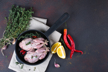 Small raw quals with some spice ready for cooking on black round pan .