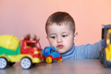 A cute little boy playing with model car collection. Toy mess in child room. Educational games for kids.