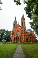Fototapeta na wymiar Rajgrod, Poland - August 22, 2017: Ancient church made from red briks and peaceful church park in little poland town Rajgrod, Poland.